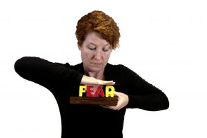 Woman smashing the word FEAR with her hands