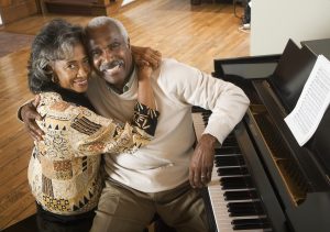 Senior African couple hugging next to piano