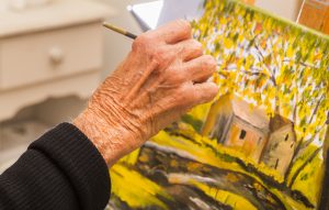 Senior woman painting, closeup of hand